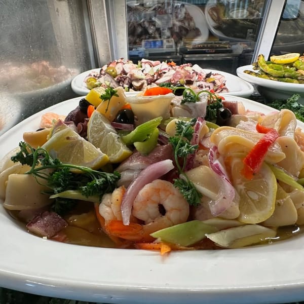 Italian seafood salad with shrimp, calamari, octopus, lemon, and parsley in a white bowl.