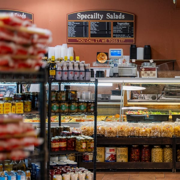 A deli counter at Taste of Italy with various Italian foods, including salads, pasta, and olives.