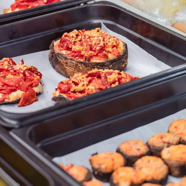 Italian stuffed mushrooms with red peppers and cheese in black serving trays.