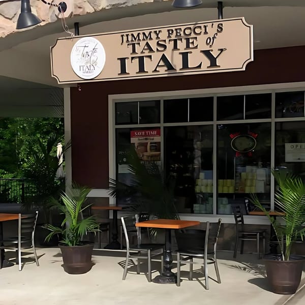 Exterior of Taste of Italy restaurant with outdoor seating, potted plants, and a large sign.